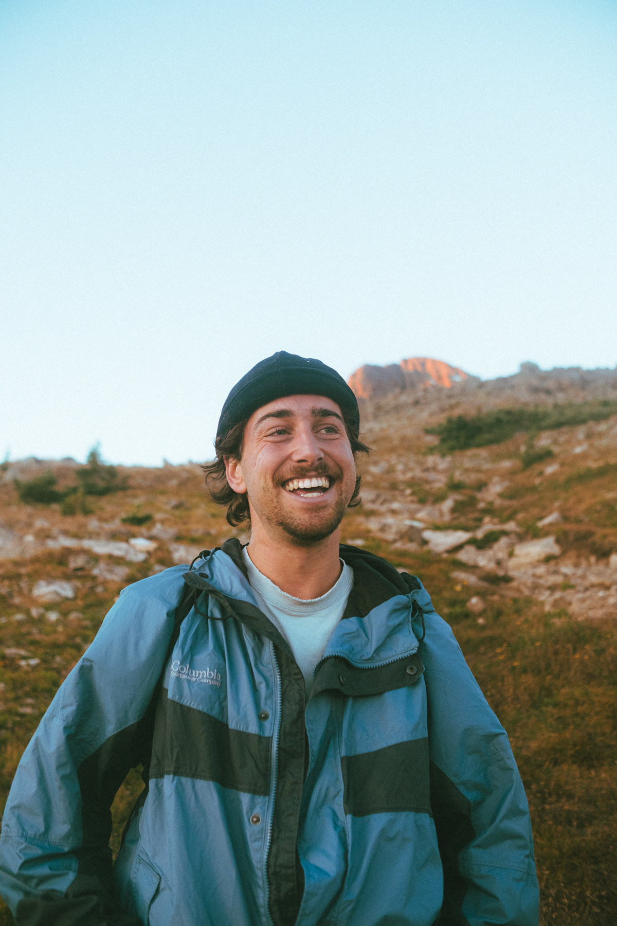 Santo laughing on a mountain trail at golden hour